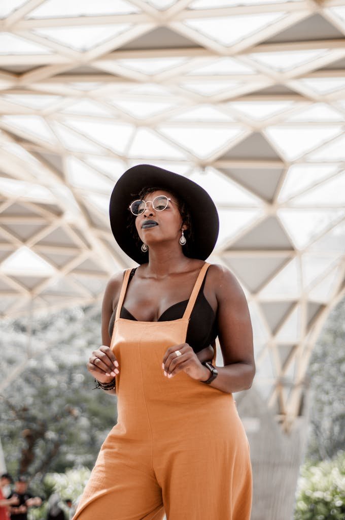 Confident woman in a stylish outfit, posing outdoors under a geometric structure.